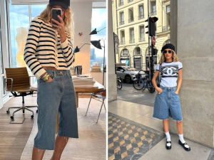 tendência Jorts. Foto mostra duas mulheres com uma bermuda longa, abaixo do joelho e tecido jeans. Uma delas tem uma camiseta de manga comprida branca e listras pretas e a outra camiseta branca com desenhos e chapéu preto. Uma usa o celular para tirar a foto, a outra posa para a foto na rua.