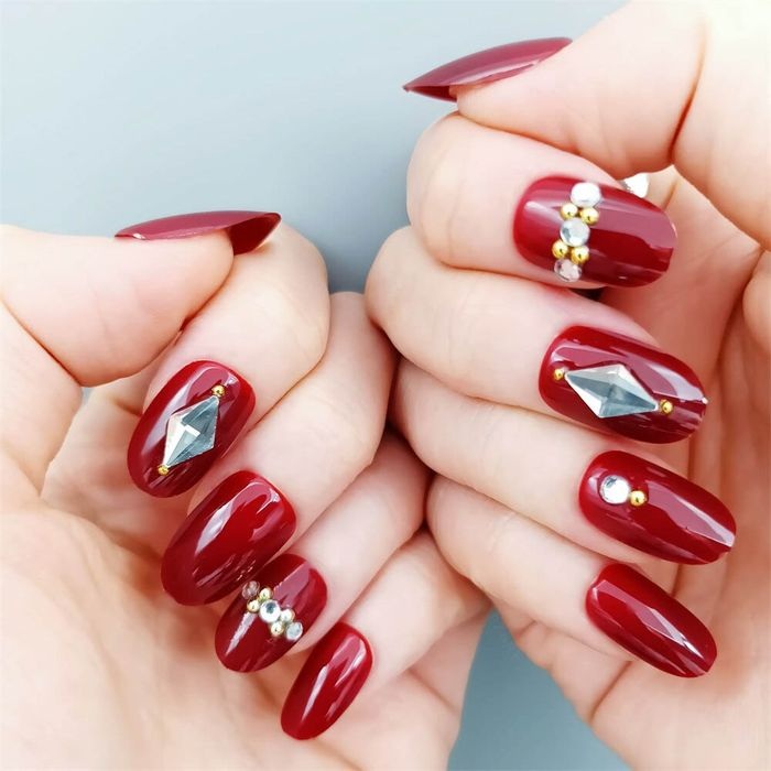 unhas vermelhas com pedras em destaque