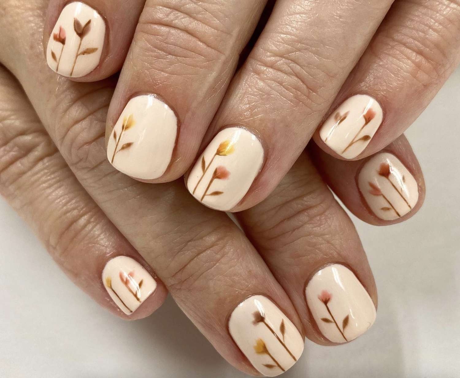 unhas em tons claros e desenhos florais sutis